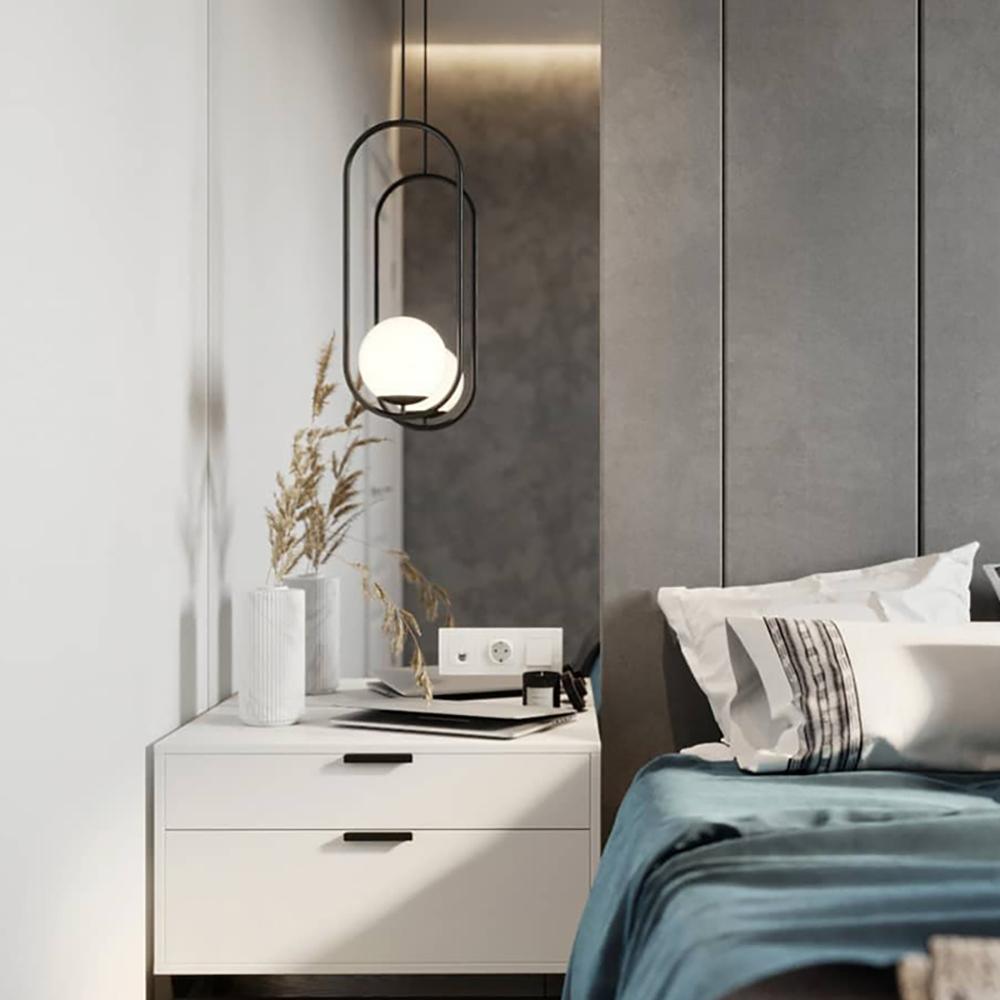 Elongated glass pendant light hanging near a wall