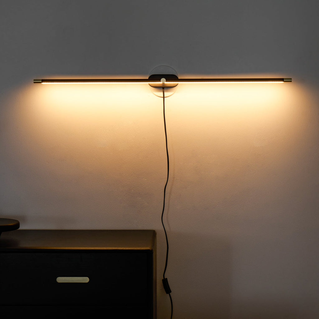 Slim wall lamp casting soft light across a wall