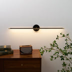 Slim black linear wall lamp lighting a gallery picture