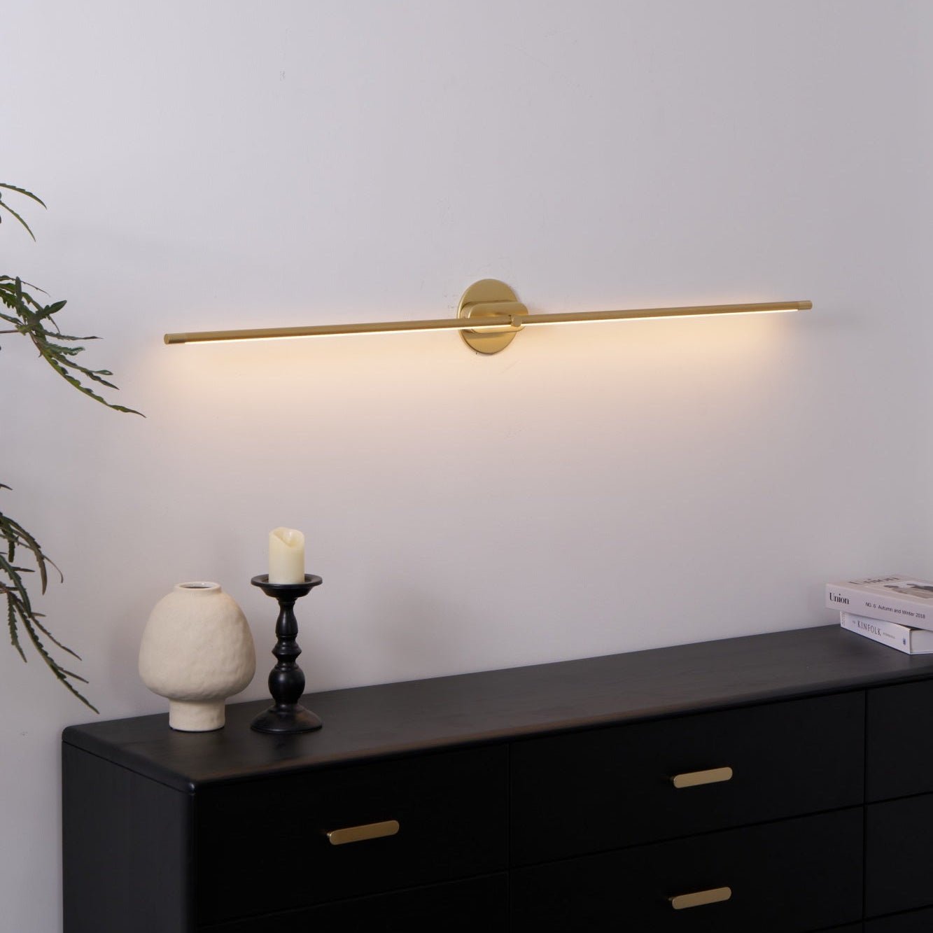 Gold linear wall lamp detail showing its slim lit diffuser