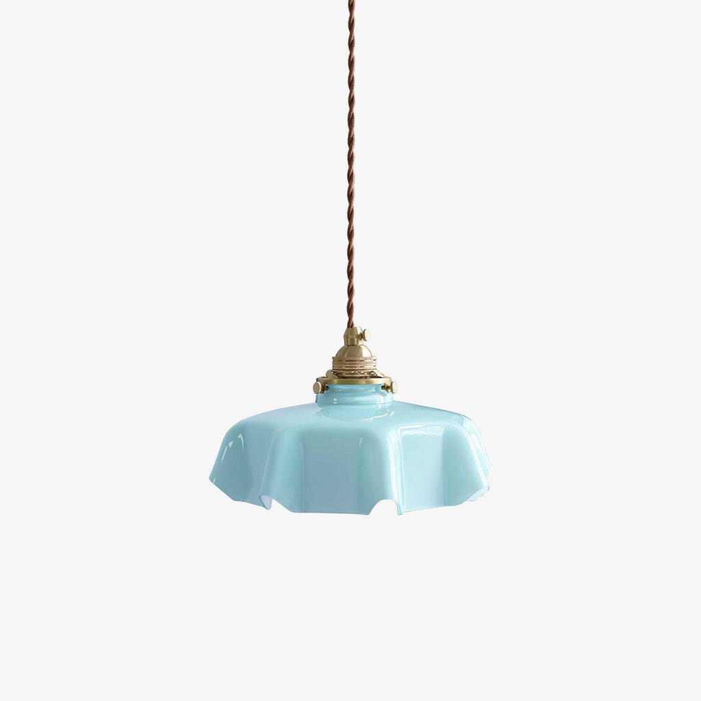 On a plain studio backdrop, this Clérachic pendant's blue pleated glass shade hangs from its brass fitter and twisted cord.
