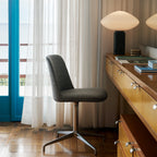 Clérachic marble table lamp lit on a distant sideboard, seen past an office chair by a window with sheer curtains.