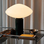 Clérachic marble table lamp on a wire-shelf bar cart, curtains behind it and a mug, books and a metal bowl close by.