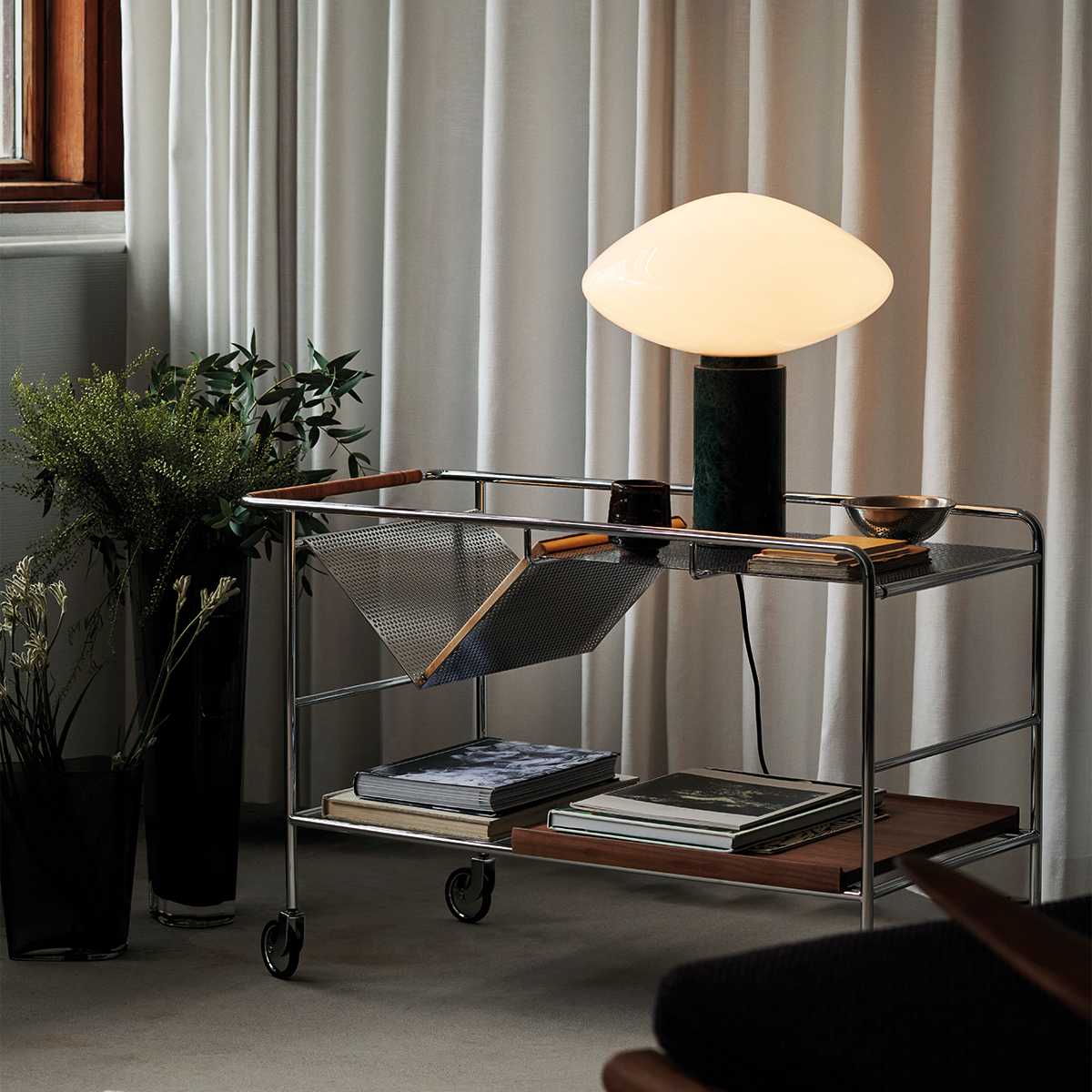 Clérachic marble table lamp lit on a wire bar cart, cropped closer on the potted plant and the cart's top shelf.