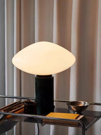 Clérachic marble table lamp lit on the same bar cart, a wider view taking in more of the books on its lower shelf.