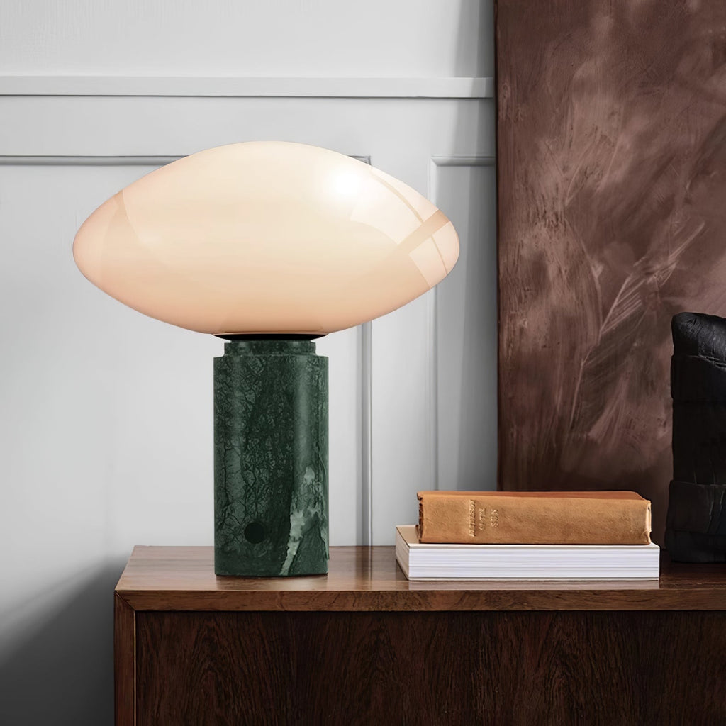 Clérachic marble table lamp on a dark wood sideboard beside a stack of books, set against a white panelled wall.