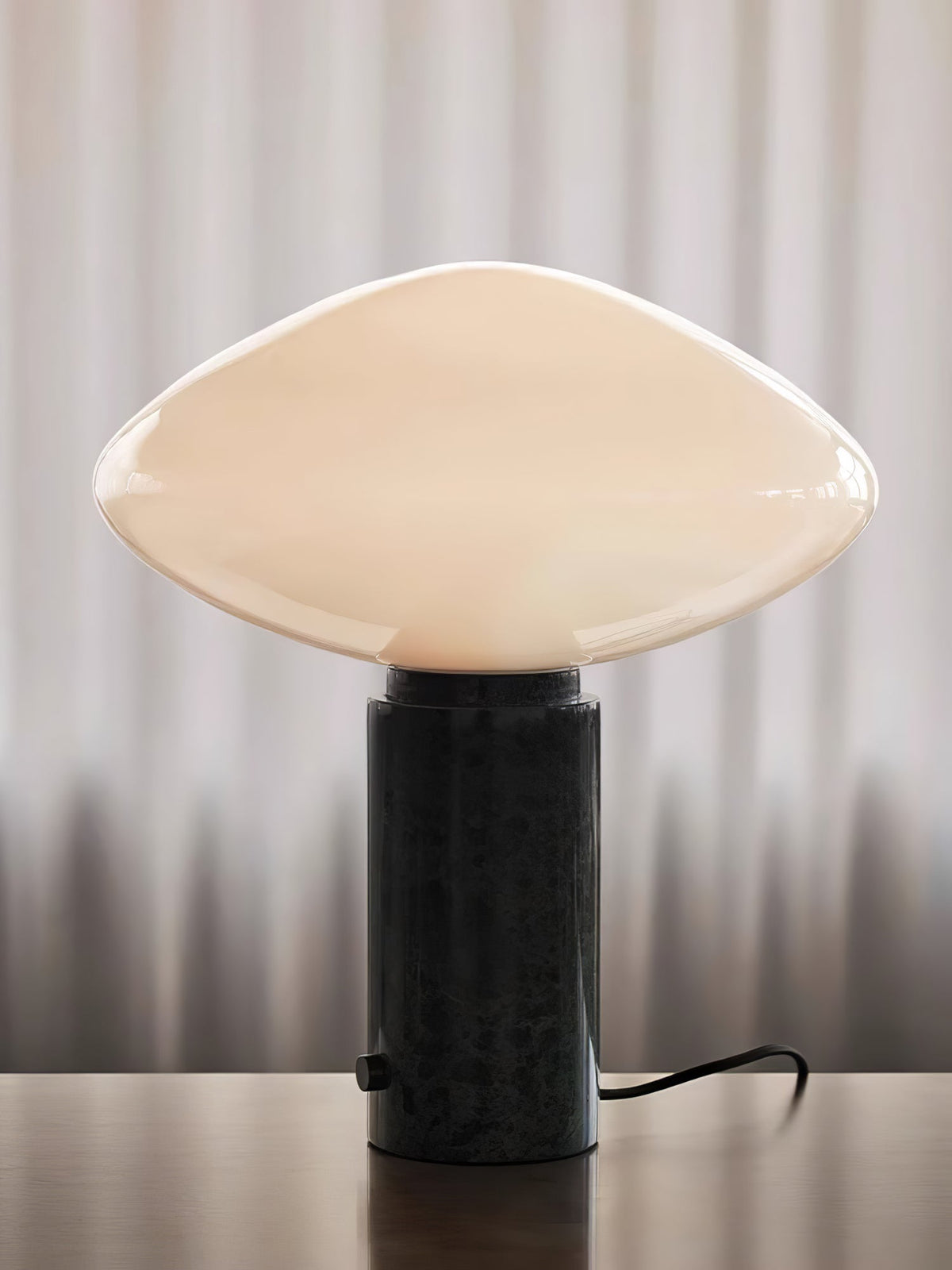 Clérachic table lamp switched off against a plain backdrop with a soft striped shadow, its dark marble base and cord visible.
