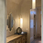 Modern glass wall lamp shown lit beside a mirror