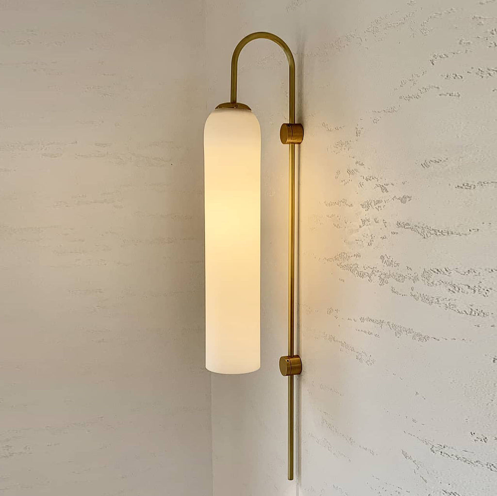 Modern glass wall lamp mounted in a hallway with warm glow