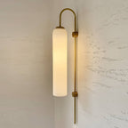 Modern glass wall lamp mounted in a hallway with warm glow