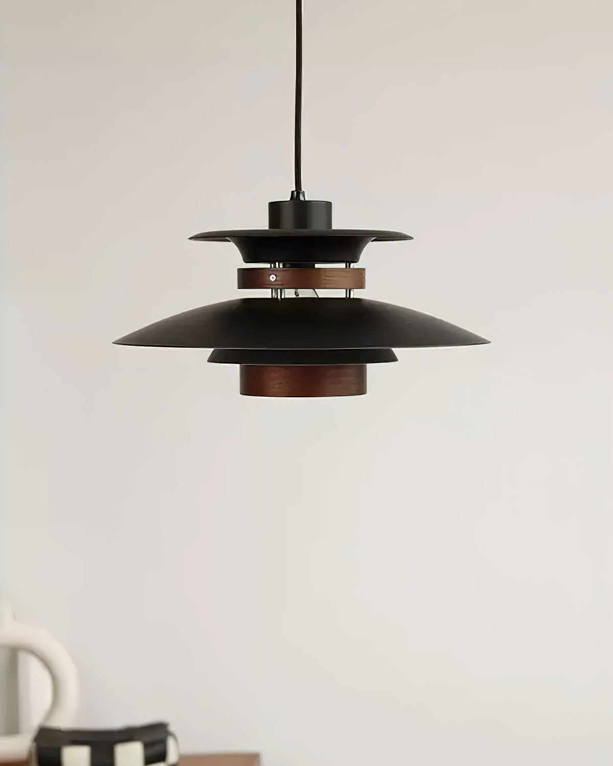 Close view of the black shades and walnut ring on this Clérachic pendant near a coffee cup.