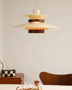 A beige Clérachic pendant hangs near a wooden dining chair and a checked storage box.