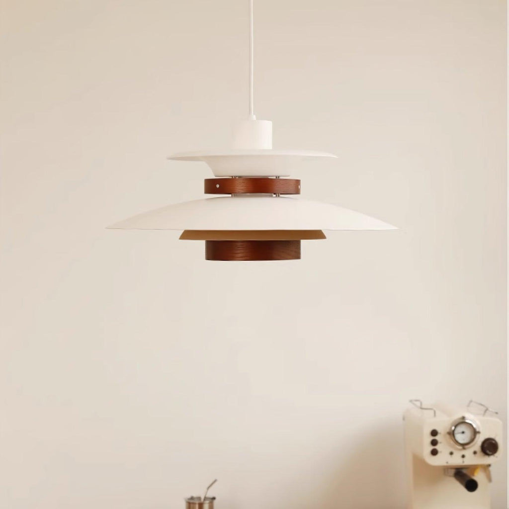A white Clérachic pendant hangs in a plain corner room with a small radio prop below.