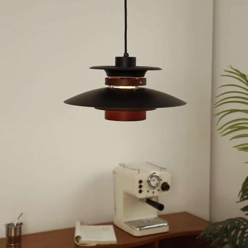 A black Clérachic pendant hangs over a wooden table with an espresso machine.