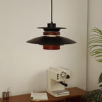 A black Clérachic pendant hangs over a wooden table with an espresso machine.