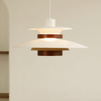 A lit white Clérachic pendant hangs near a plain wall and doorway edge.