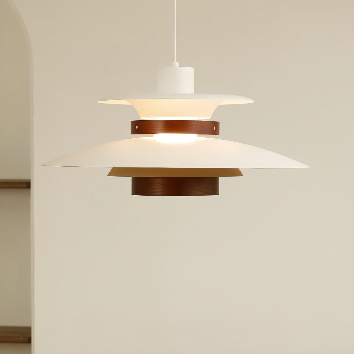 A lit white Clérachic pendant hangs near a plain wall and doorway edge.