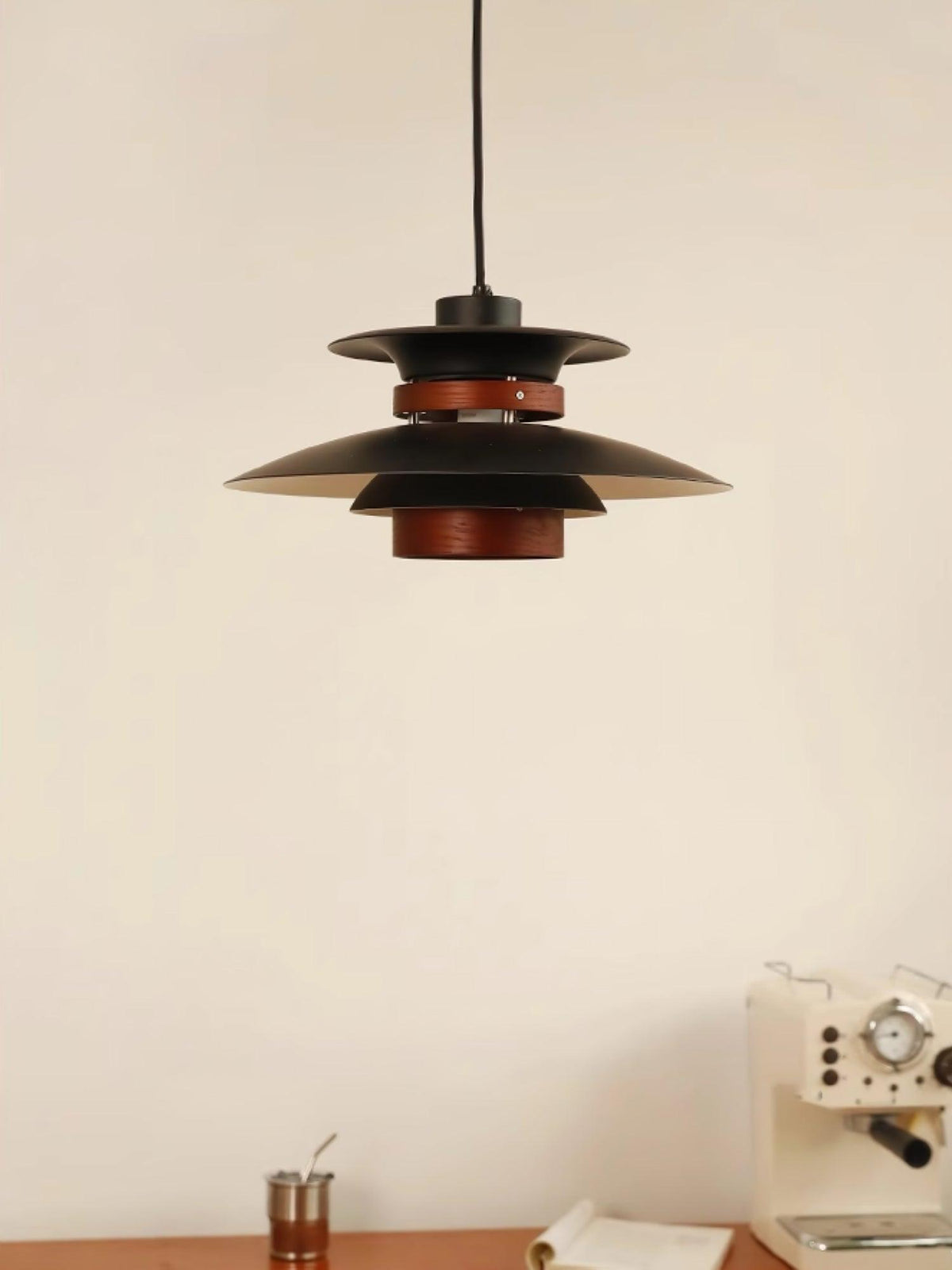 A black Clérachic pendant hangs above a desk styled with a radio prop and cup.