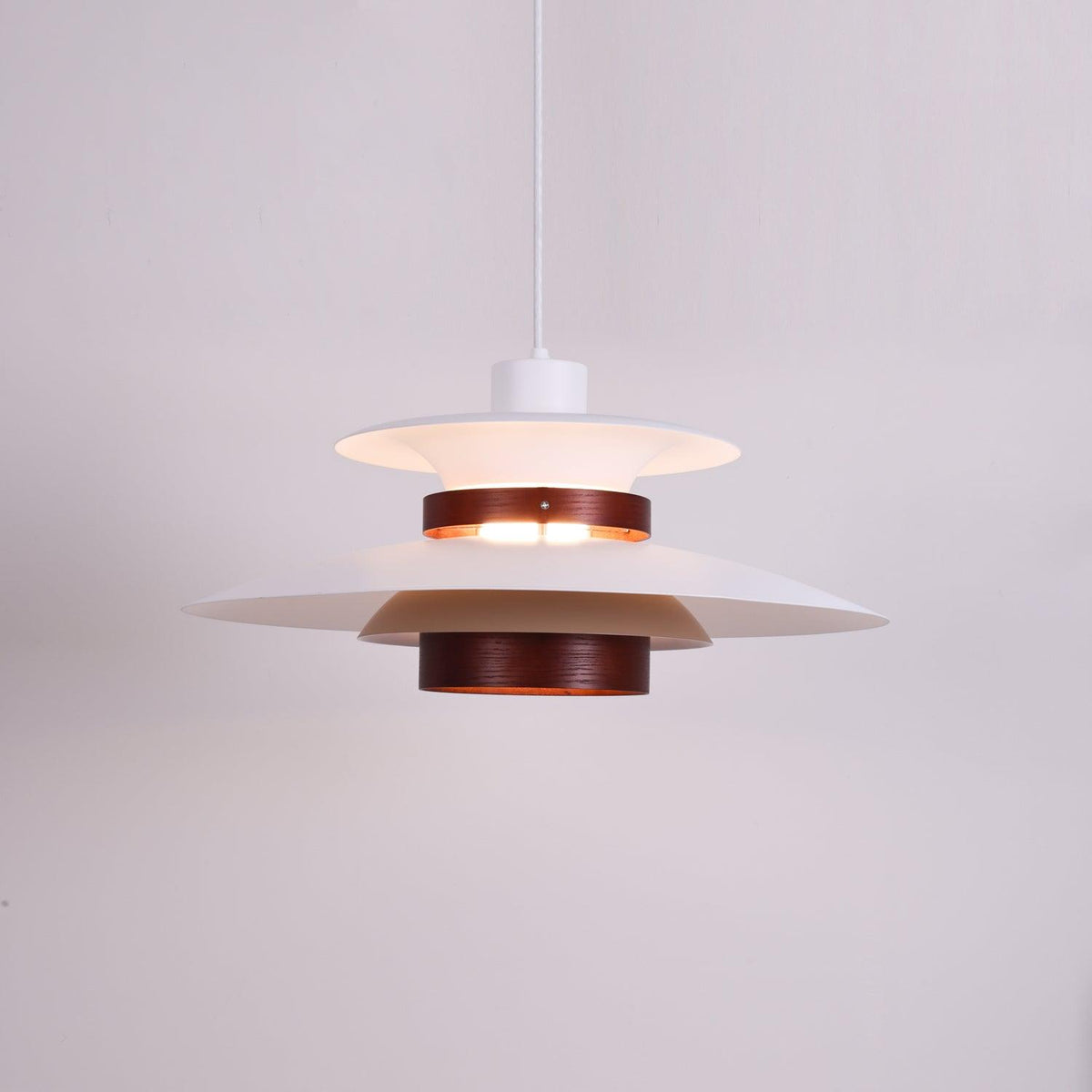 Close view of the lit white shades and walnut ring on this Clérachic pendant.