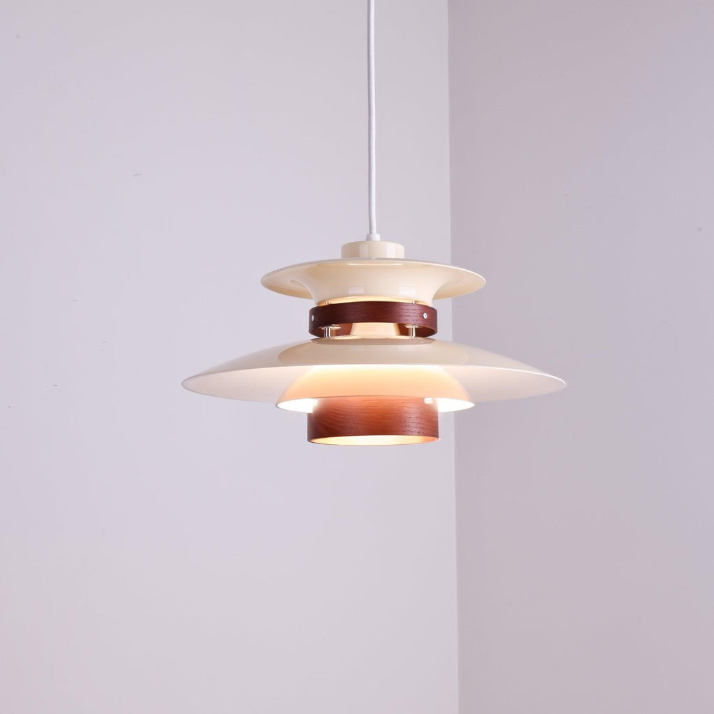 A lit beige Clérachic pendant hangs low in a plain lavender-grey corner room.