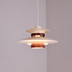 A lit beige Clérachic pendant hangs in a plain corner room, seen from a wider angle.