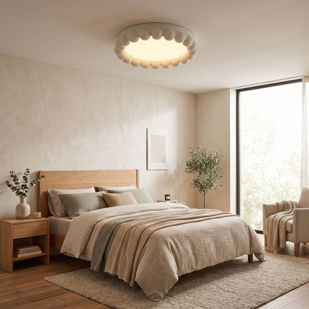 This Clérachic ceiling light in white lights a bedroom with a wooden bed frame, linen bedding and an olive tree.