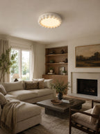 This Clérachic ceiling light in white lights a living room with a fireplace, built-in shelving and a neutral sectional sofa.