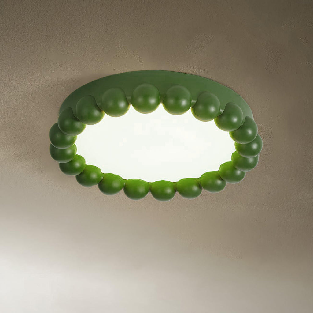 This Clérachic ceiling light in green glows softly, its beaded ring lit against a warm taupe backdrop.