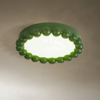 This Clérachic ceiling light in green glows softly, its beaded ring lit against a warm taupe backdrop.