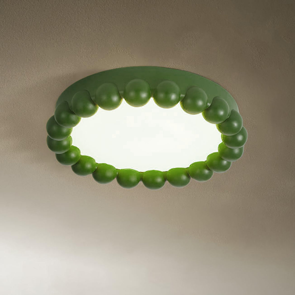 This Clérachic ceiling light in green glows softly, its beaded ring lit against a warm taupe backdrop.
