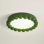 This Clérachic ceiling light in green glows softly, its acrylic diffuser lit against a plain grey backdrop.
