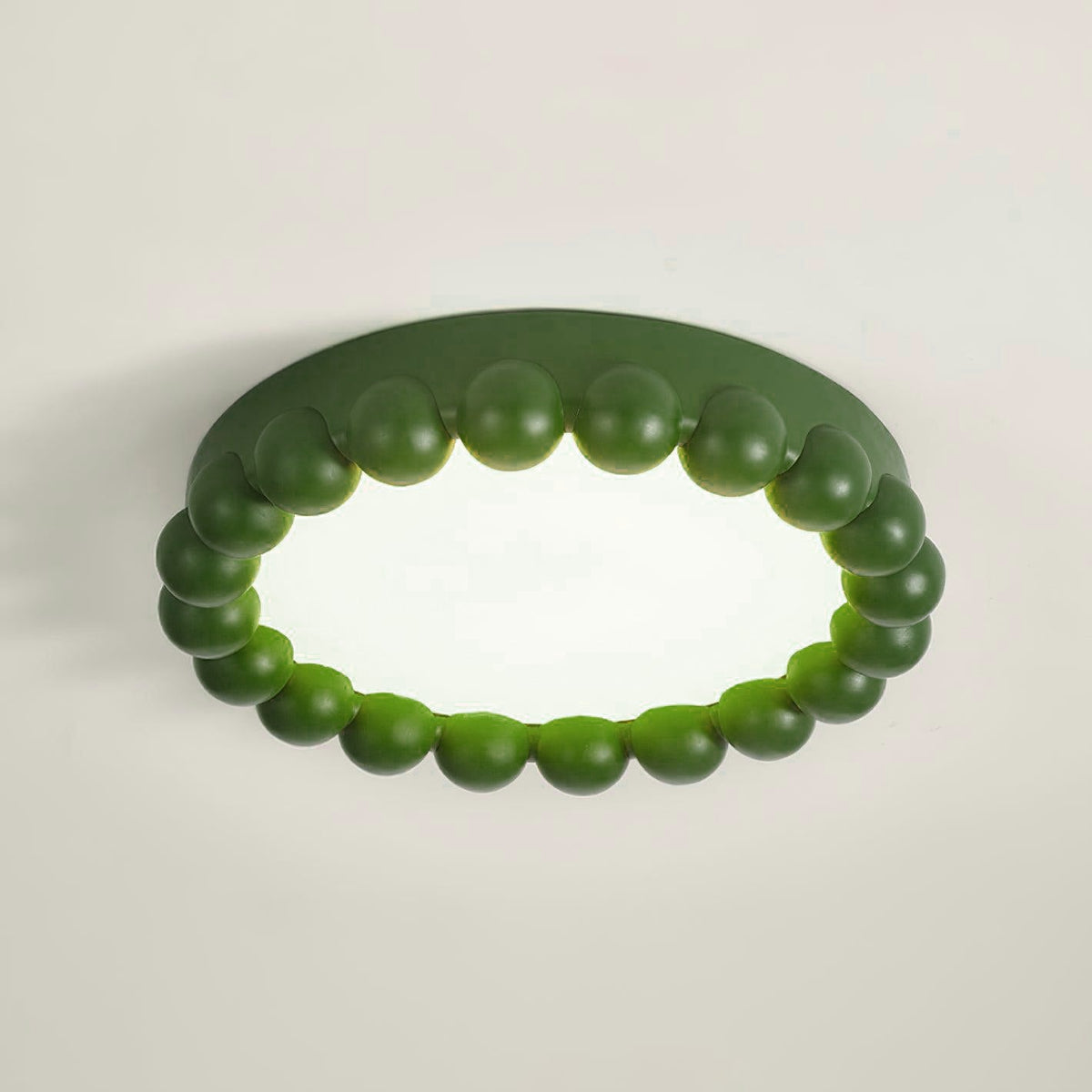 This Clérachic ceiling light in green glows softly, its acrylic diffuser lit against a plain grey backdrop.