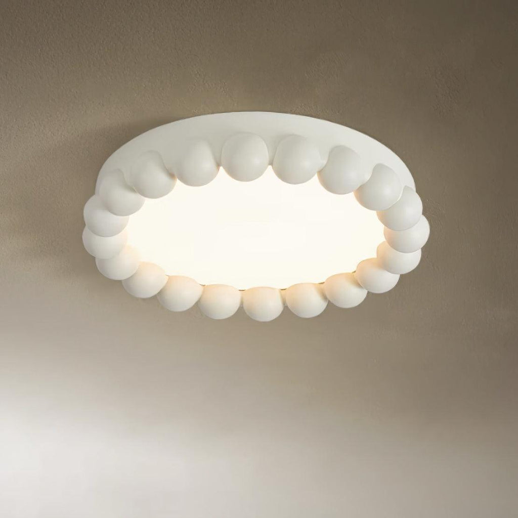 Close view of this Clérachic ceiling light in white, its beaded ring and glowing diffuser shown against a taupe backdrop.