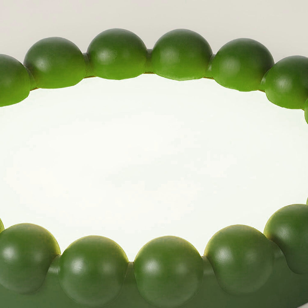 Close-up of the beaded green resin ring on this Clérachic ceiling light, its acrylic diffuser glowing white within.