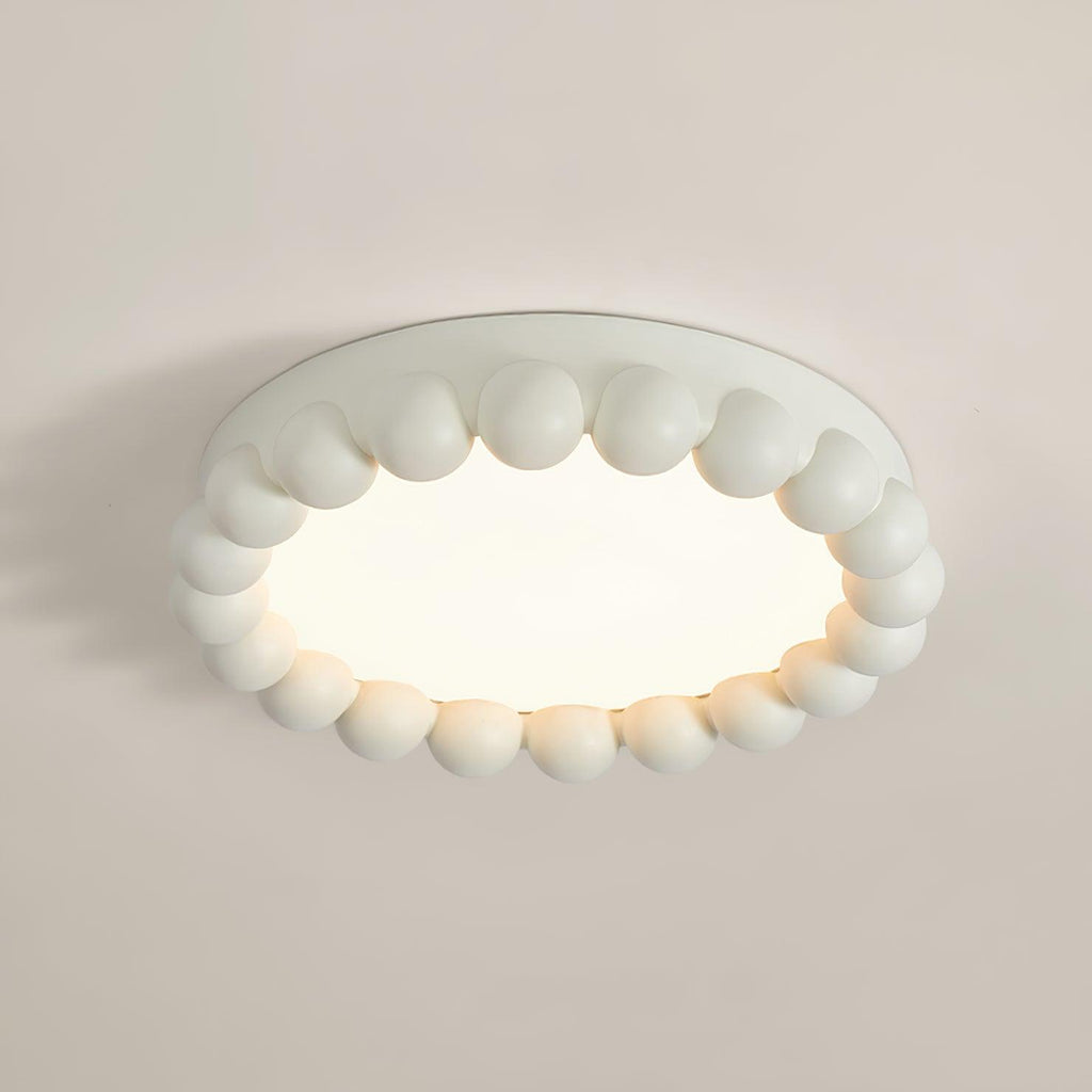 Close view of this Clérachic ceiling light in white, its beaded resin ring seen at an angle against a plain wall.