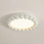 Close view of this Clérachic ceiling light in white, its beaded resin ring seen at an angle against a plain wall.