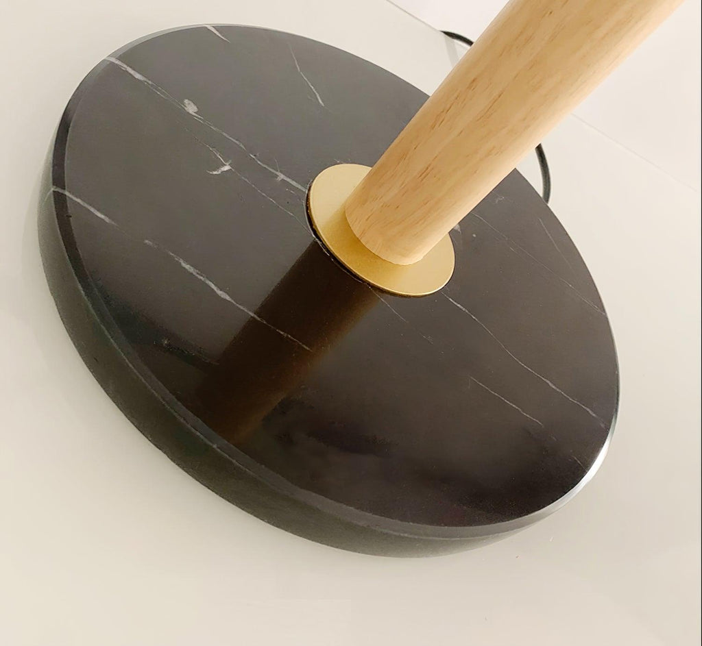Close-up of the Clérachic lamp's black marble base where the oak stem is fitted with a brass ring.