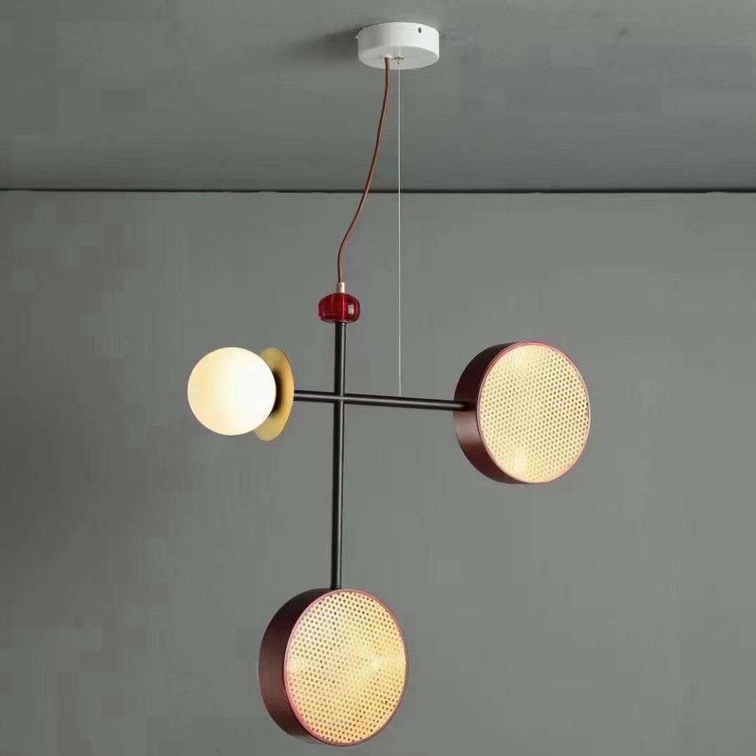 Clérachic pendant with a black rod, one cane drum and one opal glass globe, hanging against a plain grey wall.