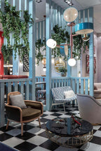 Clérachic pendant with copper and teal arms hanging among trailing houseplants above a black-and-white checkerboard floor.