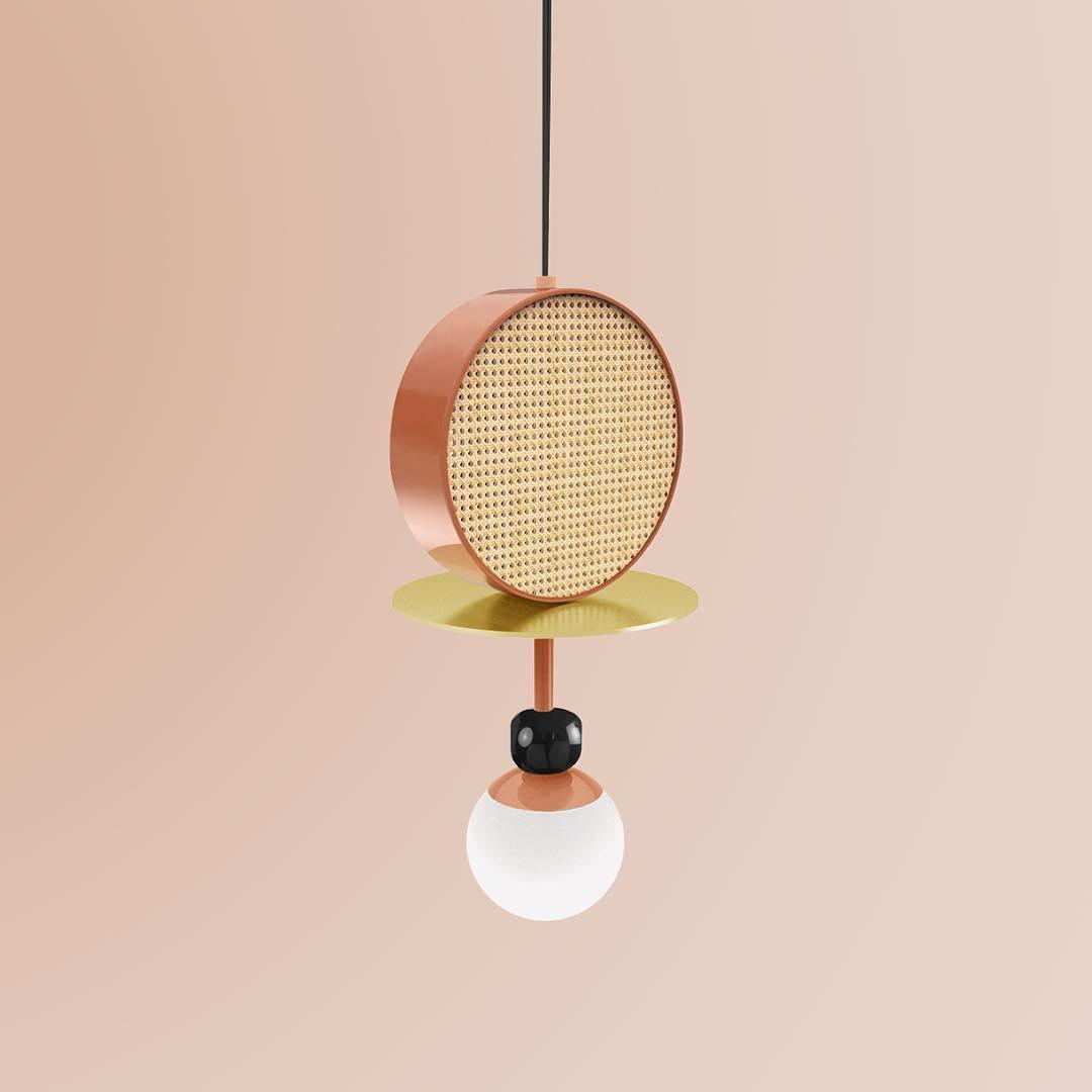 Single-arm Clérachic pendant with a copper cane drum, brass disc, dark bead joint and opal glass globe, shot against a blush pink background.