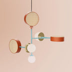 Five-arm Clérachic chandelier in coral, teal and cream tones, photographed against a dusty pink studio backdrop.