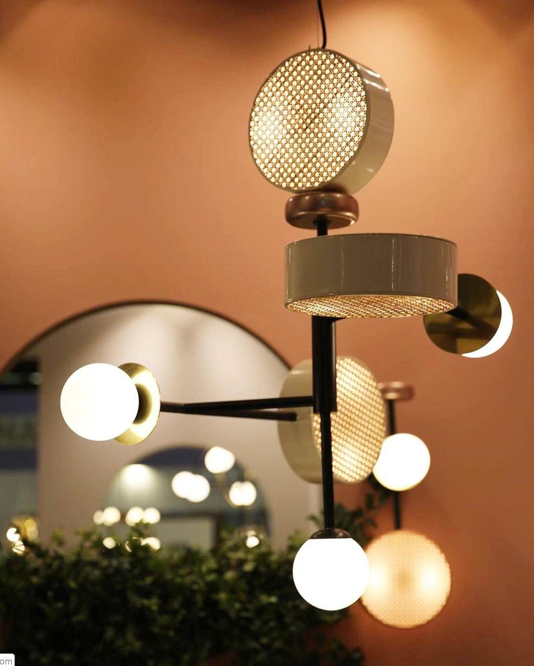 Lit cluster of Clérachic drum pendants and glass globes glowing at dusk against a warm terracotta archway.