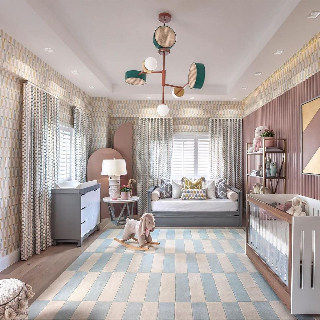 Large Clérachic chandelier centred above a crib and daybed in a patterned nursery, its coloured drums and globes catching the light.