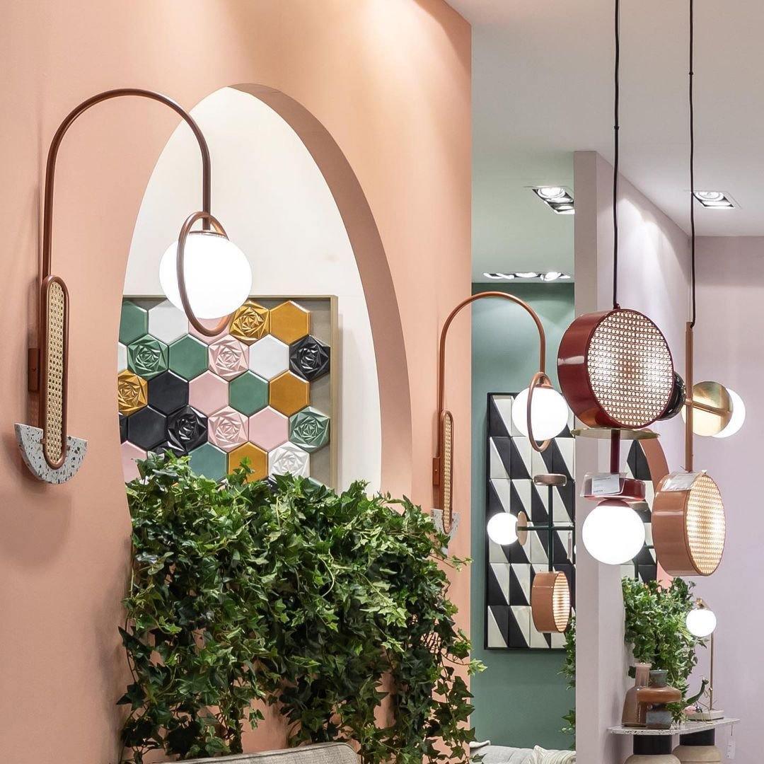 Several Clérachic drum-and-globe pendants lit above a plant-filled hallway with an arched doorway and patterned tiled wall.