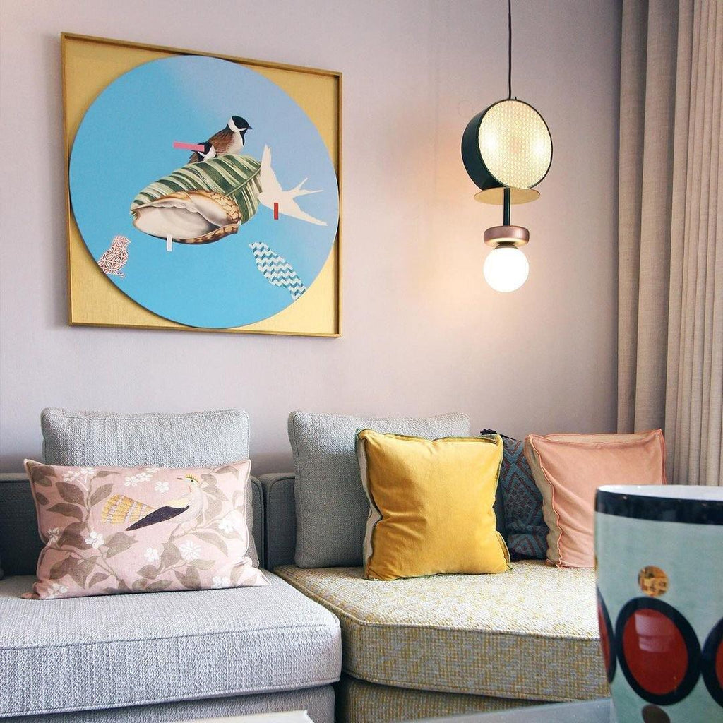 Clérachic pendant hanging above a sofa styled with patterned cushions, beneath a framed print of a bird.