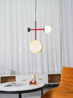 The same Clérachic pendant and orange-chaired lounge setting, cropped closer to show an open book on the table below.