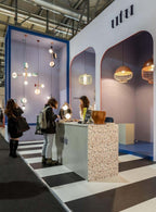 Clérachic drum pendants hanging among many other pendant styles at a lighting trade-show display.
