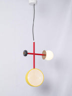Clérachic pendant with a red cross-rod, dark bead end cap, yellow-rimmed cane drum and opal glass globe, hung from a white ceiling plate.