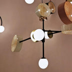Close cluster of several cane drum shades in copper and cream on a Clérachic chandelier's black frame, with globes visible between them.