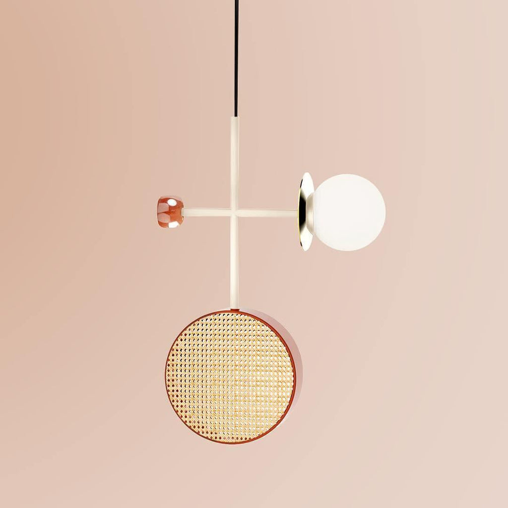 Clérachic pendant on a pale cream rod with a small copper accent disc, its cane drum and glass globe suspended against a plain blush backdrop.